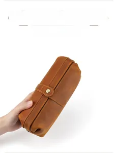 Macro shot of brown genuine leather pouch showing clear texture and hand-held portability