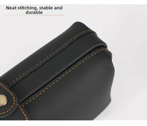 Detail of neat orange contrast stitching and bronze metal snap on black leather bag
