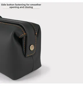 Close-up of black leather bag with orange stitching and brass snap button closure