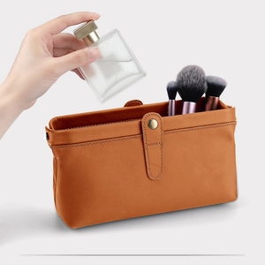 Detail of caramel brown leather toiletry bag with premium metal clasp and stitch texture