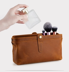 Macro detail of dark brown vintage leather cosmetic bag with bronze buckle and brushes