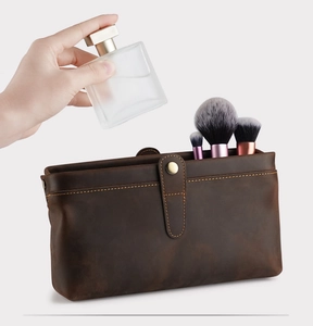 Action shot of placing perfume into a large capacity vintage brown leather toiletry bag