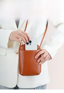 Brown litchi grain leather mini crossbody phone bag shown on white blazer and jeans