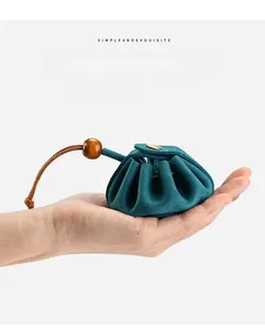 Close-up of a palm-sized teal genuine leather coin purse with wooden bead and snap button