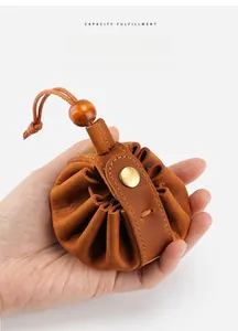 Handheld view showing compact size of the brown crazy horse leather drawstring coin pouch