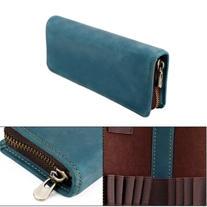 Detalle de estuche de cuero azul con cremallera vintage y ranuras elásticas internas