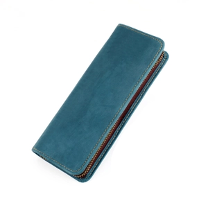 Detalle de estuche de cuero turquesa con costuras amarillas y cremallera metálica retro