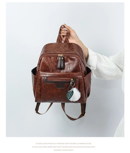 Close-up of a brown PU leather vintage backpack with leaf charm and zip pockets