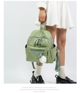 Detailed view of light green PU leather backpack with multiple zipper pockets and plush charm