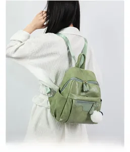 Detailed view of grass green PU leather backpack with multi-layer zippers and fur ball charm
