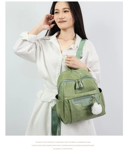 Detail of Morandi green PU leather backpack with zippers and a white pom-pom pendant