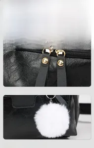 Detail of black leather backpack with gold double zippers and white fur ball pendant
