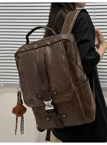 Side view of dark brown PU leather backpack with decorative straps and plush bear charm