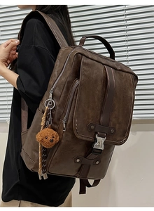 Detail view of the deep brown vintage PU leather backpack with a cute teddy bear charm