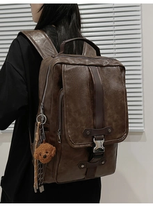 Detail shot of vintage brown PU leather backpack with a plush bear charm on the side