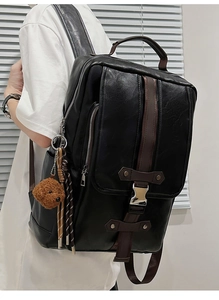 Detail of black faux leather backpack featuring vintage metal buckles and side teddy charm