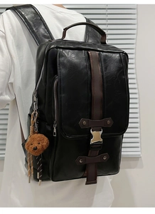 Close-up of black PU leather backpack with silver buckles and a brown bear pendant