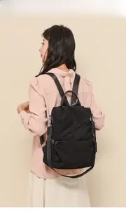 Detail of black corduroy backpack with leather handle and side pocket on a female model