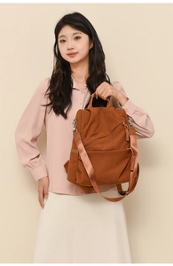 Detail of brown corduroy backpack showing textured fabric and adjustable woven strap