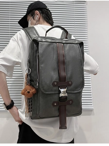 Detail of grey PU leather backpack with vintage buckles and brown bear pendant