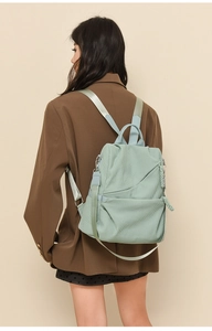 Detail of mint green corduroy backpack with light blue straps shown on a model