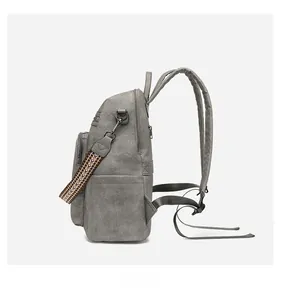 Side view of grey leather backpack featuring multi-pocket structure and ethnic woven strap