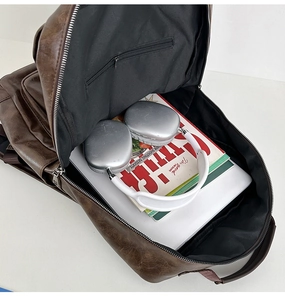 Spacious interior of brown PU leather backpack with laptop and accessories inside