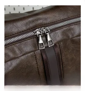 Detail shot of smooth double metal zippers on a brown textured leather backpack