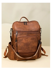 Close-up of vintage brown PU leather backpack with tassel and geometric woven strap