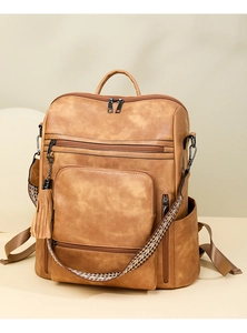 Detail of caramel PU leather backpack featuring ethnic straps and a tassel charm