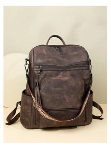 Macro detail of dark brown PU leather backpack with ethnic woven strap and tassel