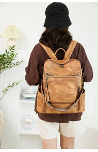 Close-up of vintage brown leather backpack featuring fringe tassel zipper and side pockets