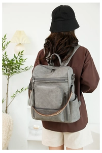 Detail of grey PU leather backpack with vintage texture and colorful woven strap