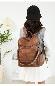Detail of vintage brown PU leather backpack with woven strap and tassel accessory