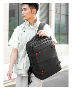 Side view of large black business backpack with red buckles on a male model in urban setting
