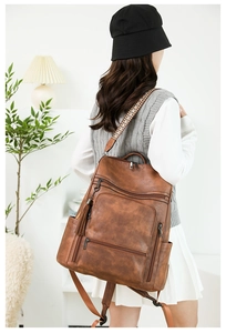 Detail of vintage brown leather backpack with ethnic woven straps and tassel decor