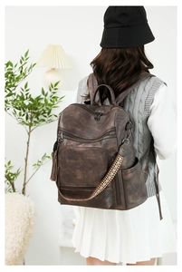 Rear view of vintage brown PU leather backpack with colorful bohemian strap on a model
