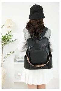 Detail of black PU leather backpack with metallic zippers and woven geometric shoulder strap