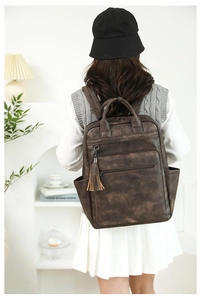 Detail view of a vintage dark brown PU leather backpack with a tassel on a model