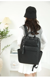 Lifestyle shot of black faux leather backpack featuring tassel detail and multiple pockets