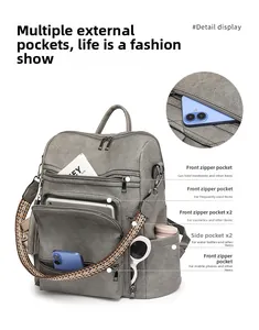 Detailed view of large grey PU leather backpack showing multi-pocket storage and woven strap
