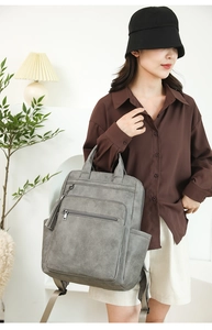 Close-up of grey PU leather backpack with tassel detail and functional metal zippers