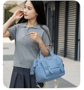 Light blue canvas crossbody bag shown with a grey knit polo shirt and pleated skirt