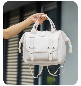 Detail of a beige multi-functional diaper backpack with leather straps and durable handles