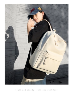 Outdoor street shot of a minimalist off-white oxford backpack with multiple pockets