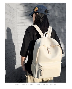 Outdoor street shot of a minimalist cream oxford backpack worn by a female model