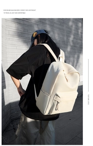 Minimalist cream white backpack shown from behind on a model against a textured wall