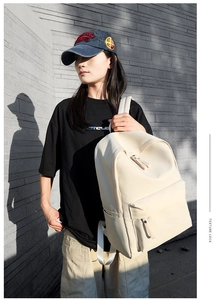 Minimalist cream oxford backpack shown on model with striped urban wall background