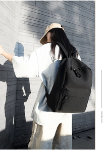 Close-up of a minimalist black oxford backpack featuring a large front zipper pocket