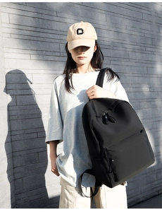 Outdoor lifestyle shot showing a black oxford fabric backpack with a large front zip pocket